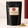 Sachet de poudre de Tabrima Hinalya 100 g pour le rituel corps et hammam, sur fond ivoire et bordeaux